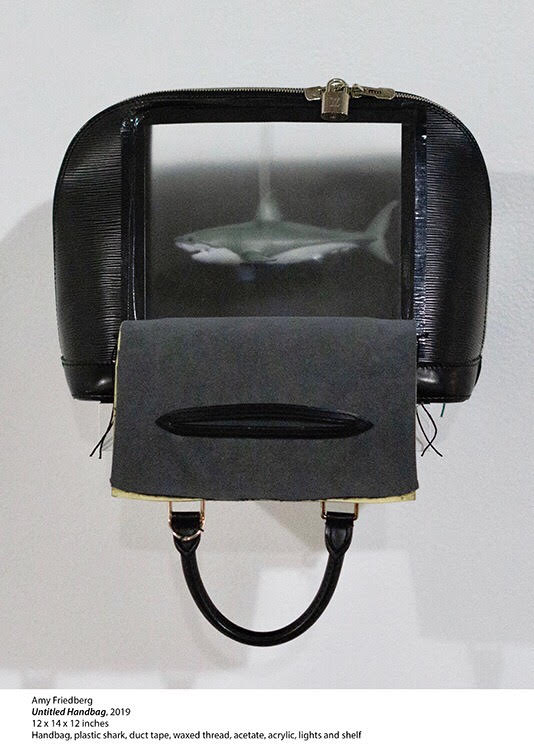 "Untitled Handbag" by Amy Friedberg, 2019. Handbag, plastic shark, duct tape, waxed thread, acetate, acrylic, lights and shelf, 12 x 14 x 12 inches.