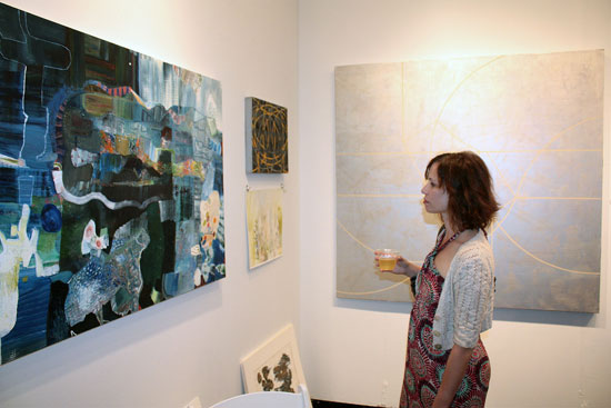 Artist Andrea Cote examines a painting.