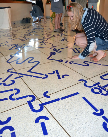 A participant considers the choices in applying their four blue stickers to "Ultramarine Fungus", 2014, at NADA Miami Beach. Photo by Pat Rogers.