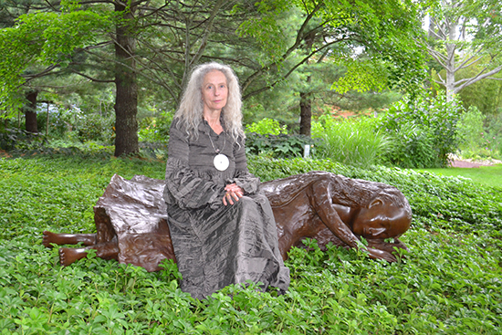 Kiki Smith sitting on one of her "Woman With Sheep" sculptures. Photo by Dawn Watson. 