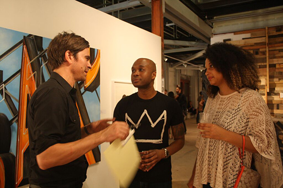 Greg Lundgren, right, one of the curators of “Out of Sight”, talks with art goers at the Opening. Photo by Amber Cortes.