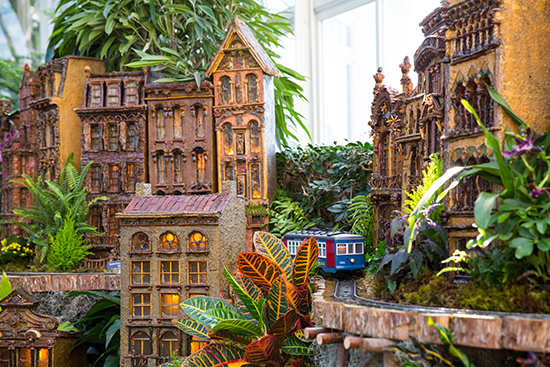 A blue trolley passes by NYC landmark buildings. Holiday Train Show ® Photo by Ben Hider 