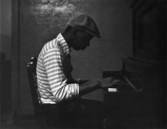 "Man in striped shirt at piano" by Roy DeCarava, 1954.