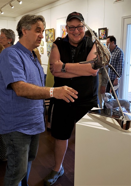 Exhibiting artist Michael Cardacino explains the finer points of his sculpture "Emptiness of Shark" to Terry Ross. The artwork is 3D printed, metabolized and polished. Photo: Pat Rogers. 